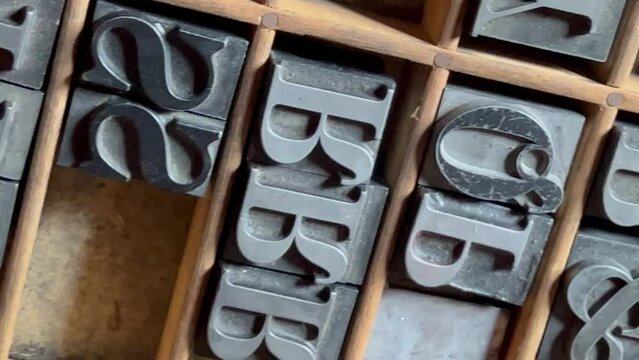 Individual pieces of metal type stored in a wooden type case